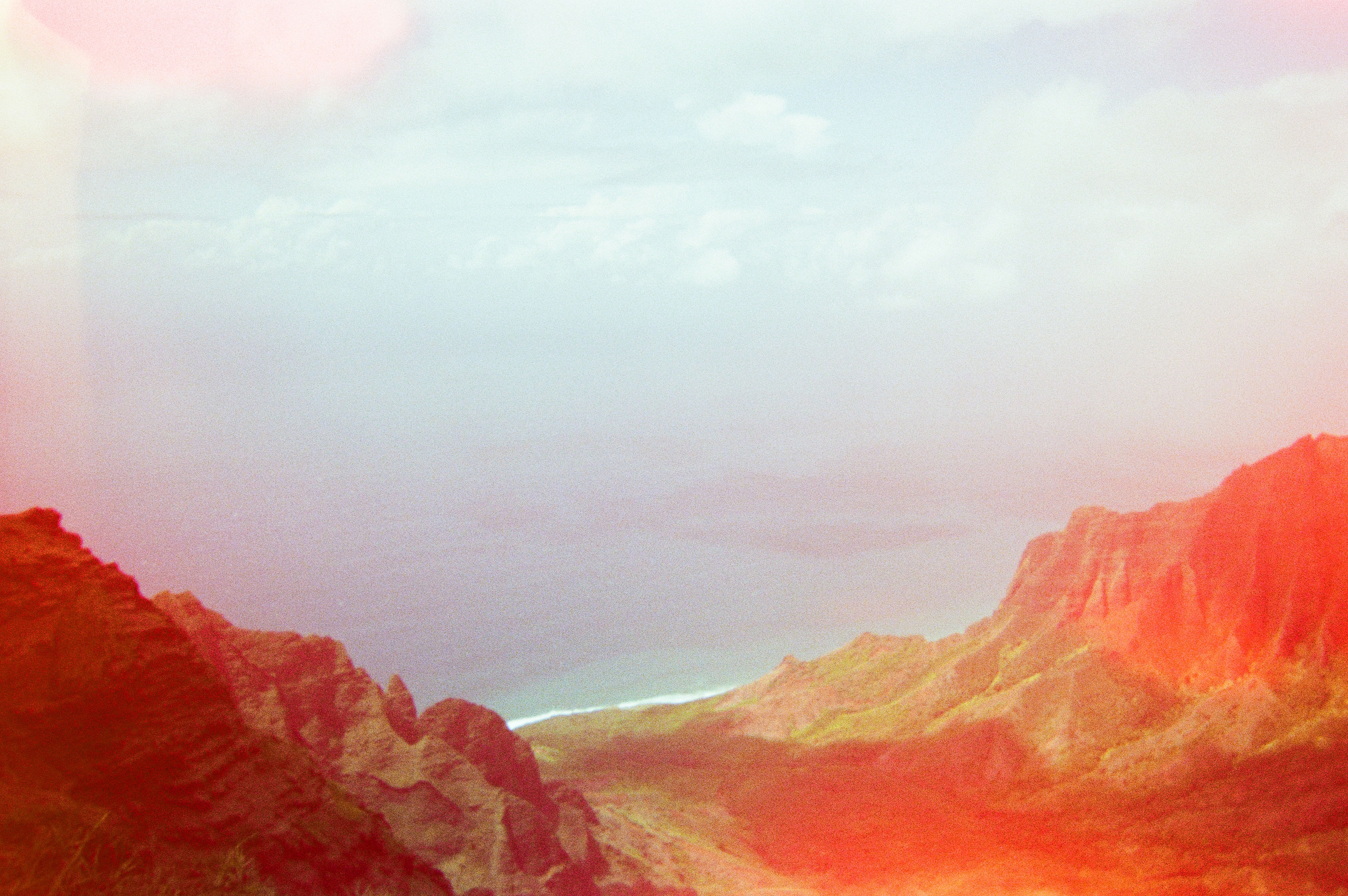 Mountain valley opening to the ocean at sunset with warm pink light